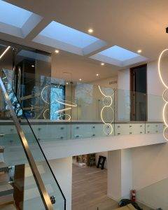 A modern staircase enclosed in glass, with dark treads and a minimalist handrail